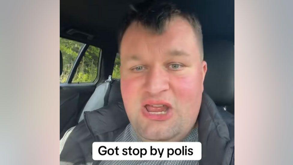 A man in a car appearing in a TikTok video with the caption Got stop by polis at the bottom of the screen