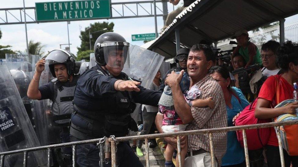 A Mexican riot policeman protects an immigrant father and child during a clash between police and the migrant caravan on the border between Mexico and Guatemala on 19 October 2018 in Ciudad Tecun Uman, Guatemala.