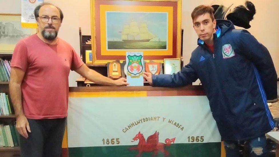 David and Daniel Hughes - President of Saint David's Association in Patagonia - pose for a picture while holding a plaque with the Wrexham badge