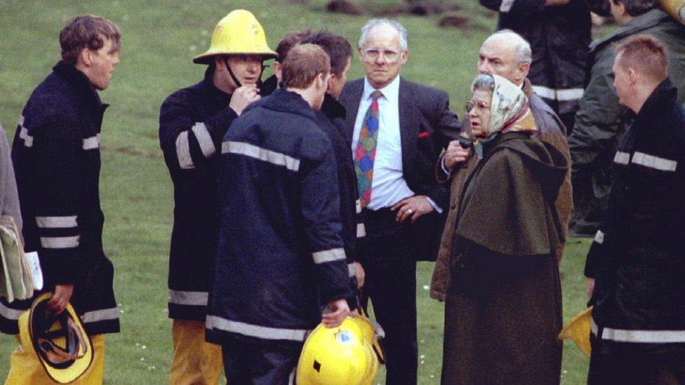 Queen Elizabeth II stands with firefighters after a fire broke out in a private chapel during building work at Windsor Castle, Britain, November 20, 1992.