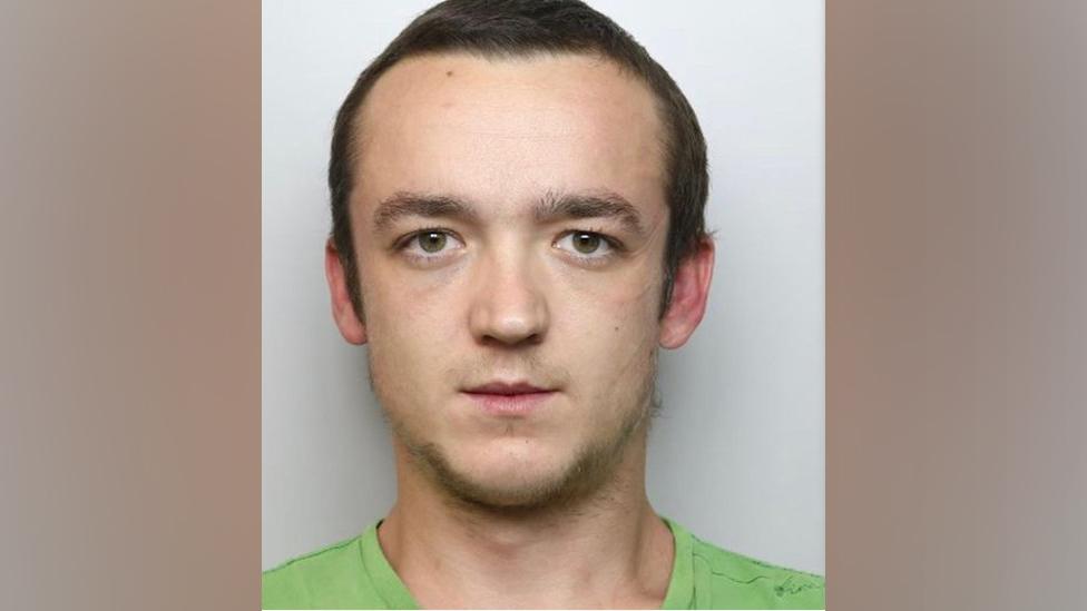 Man with short dark brown hair wearing green t-shirt