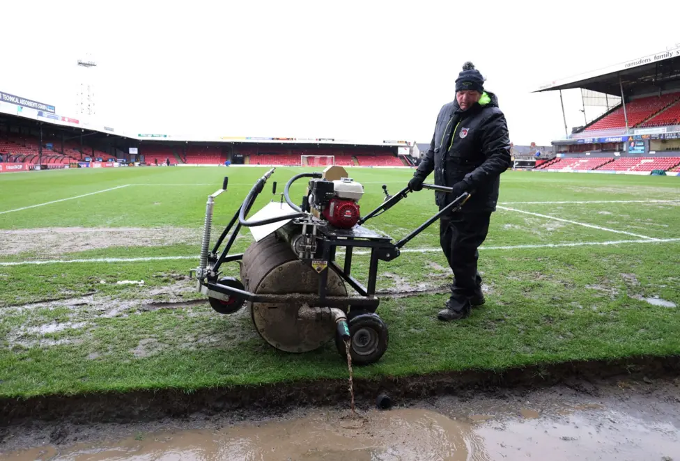 Grimsby Town ground staff attempt to drain the pitch before kick-off