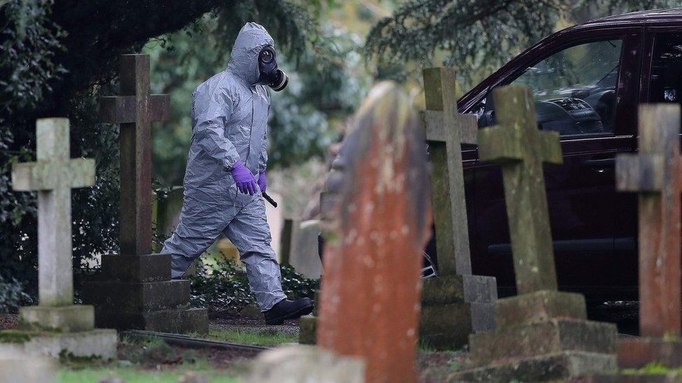 A man in a hazmat suit walks through Salisbury cemetery