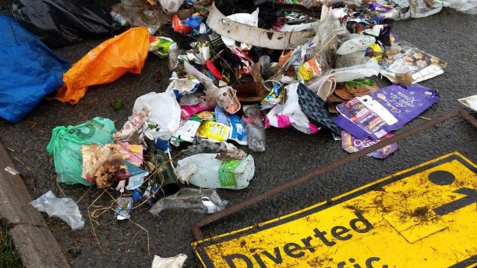 A diverted traffic sign with litter around it