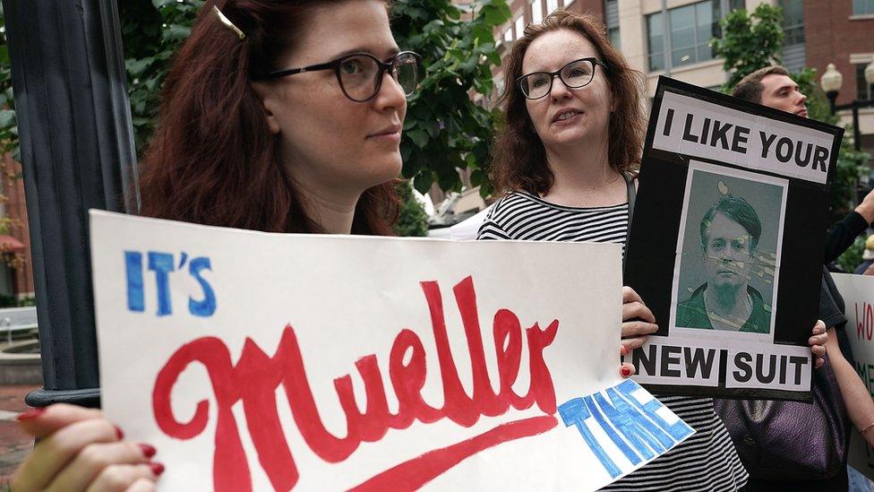 Activists hold signs during a protest outside court prior to the first day of the trial of former Trump campaign chairman Paul Manafort July 31, 2018 in Alexandria, Virginia