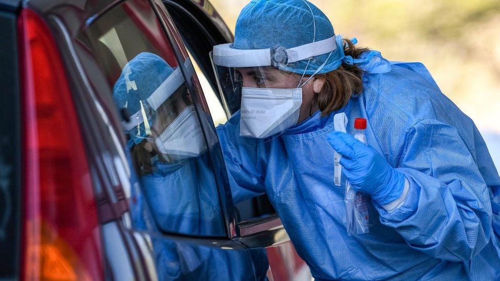 A health worker performs a test on a person in a car