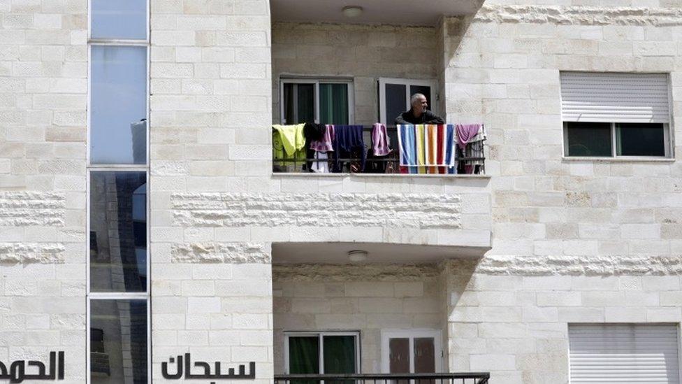 A man looks out from his balcony in Amman, Jordan