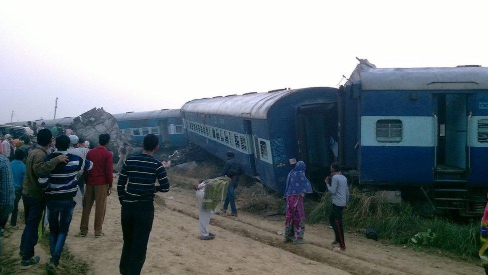 People look at the wreck on the train which came off the tracks in India