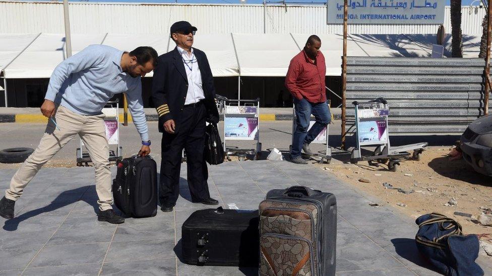 A crew member stands outside the Mitiga International Airport