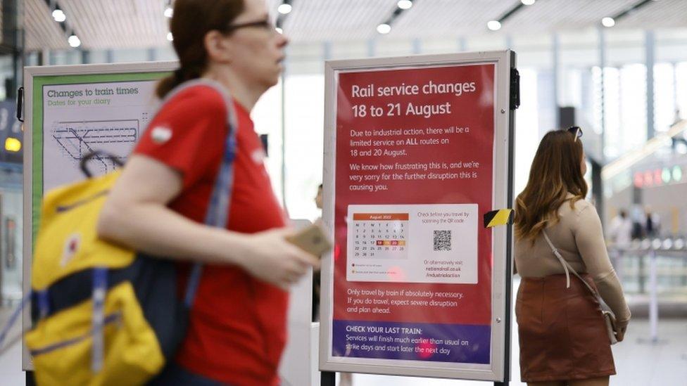 people walking past a sign showing when the train strikes will be