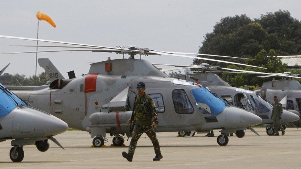 A soldier in the Philippines walks in front of a helicopter