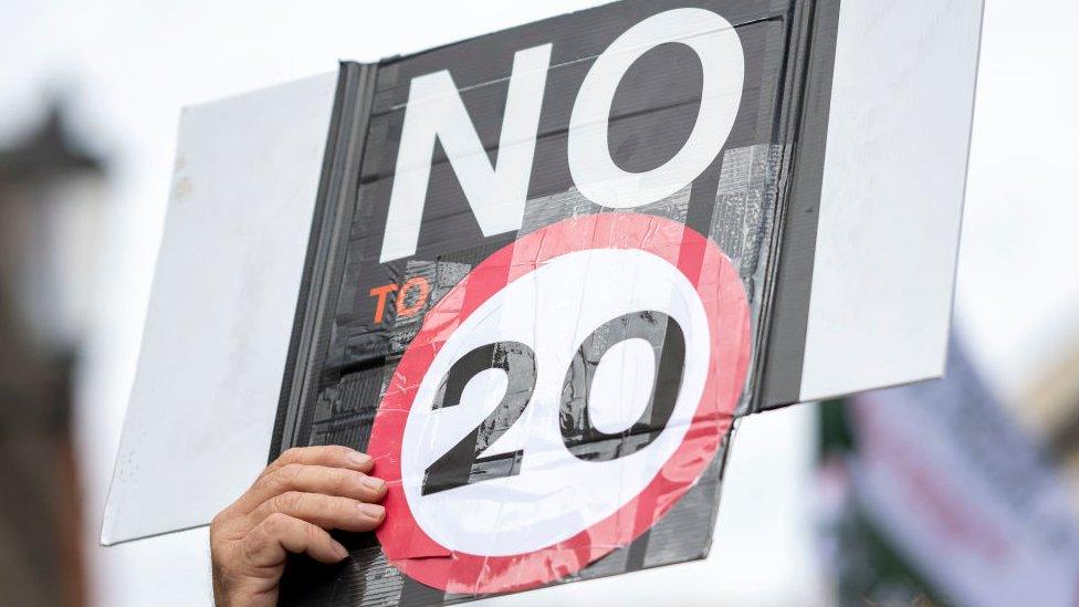 A man holds a sign during a protest against 20mph speed limits on Welsh roads