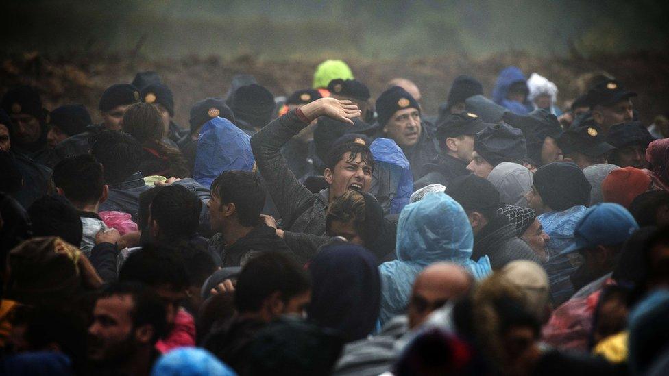 Croatian police officers stand guard as migrants wait to enter Croatia from the Serbia-Croatia border, near the western Serbian village of Berkasovo, on October 19, 2015.