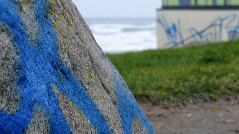 Large rock and building with graffiti on it