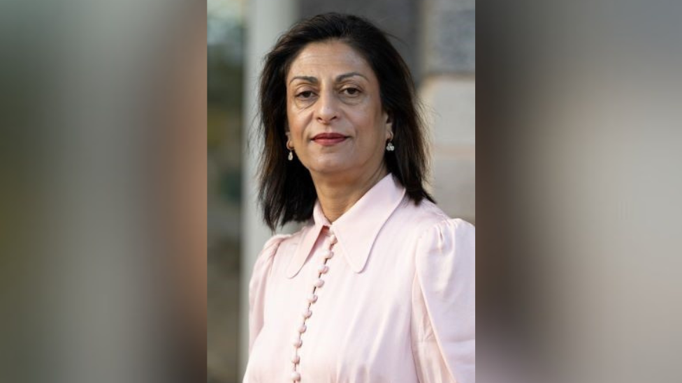 A woman with dark hair in a pink blouse