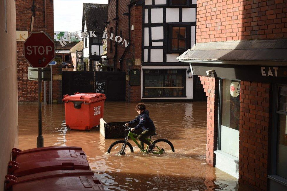 A boy cycles through flood water in Hereford.