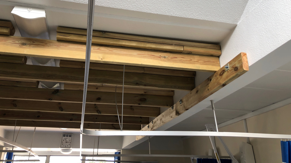 A close-up of wooden rafters resting on a wooden beam propping up a ceiling in a hospital 