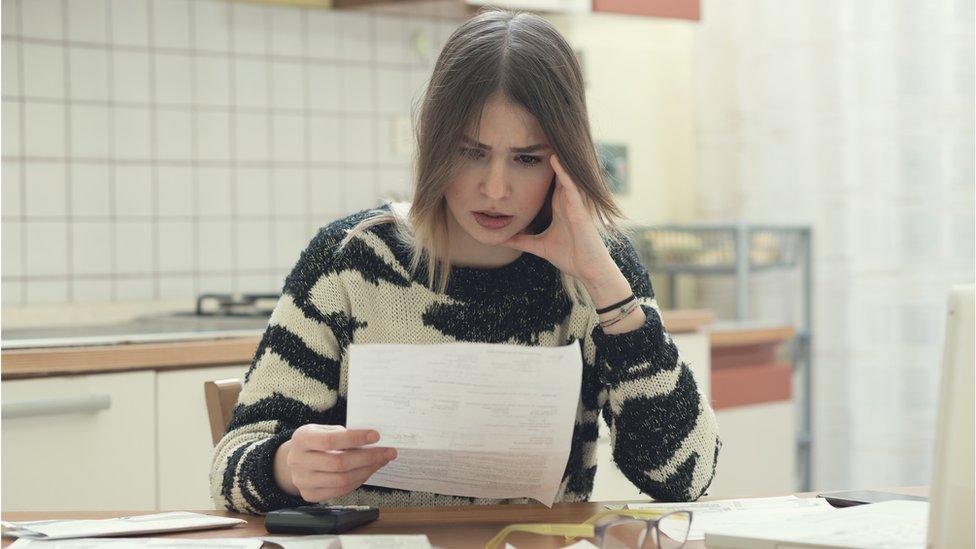 a woman looks at a bill