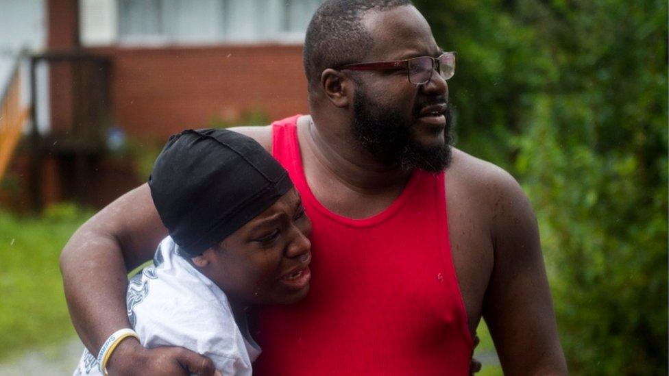 A father and daughter appear emotional as a neighbour is taken away injured from fallen tree