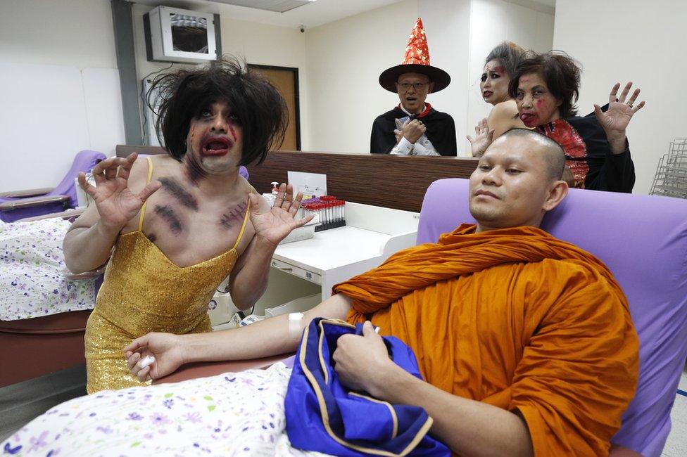 A man donates his blood surrounded by staff in horror costumes