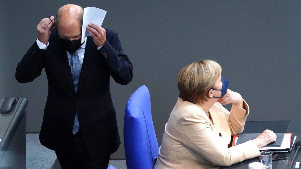 German Minister of Finance and Social Democratic Party (SPD), top candidate for the federal elections Olaf Scholz (L) passes by German Chancellor Angela Merkel