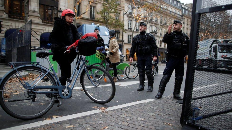 A woman walks with a bicycle as French police block a street near the Place de la Concorde in Paris