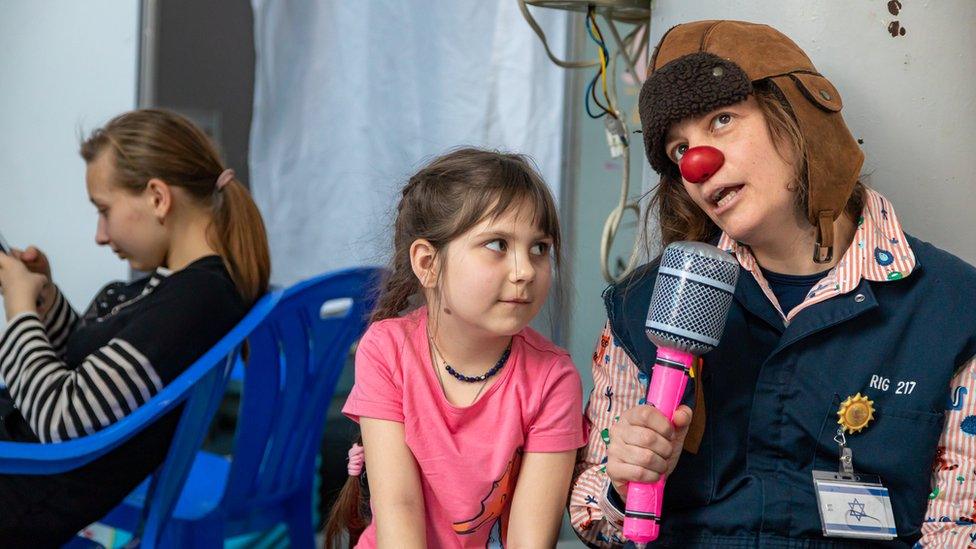 Smadar the Clown from the aid group The Dream Doctors Project pretends to interview a young Ukrainian girl at a refugee centre set up at the International Exhibition Centre MoldExpo, on 10 March 2022 in Chisinau.