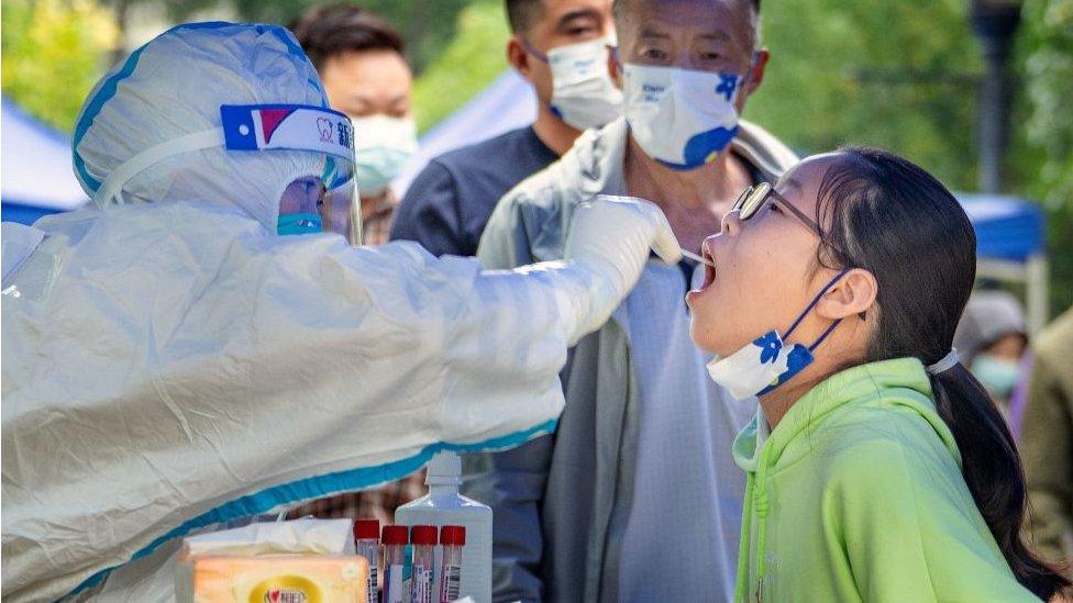 This photo taken on September 17, 2022 shows a health worker taking a swab sample from a young resident to be tested for the Covid-19 coronavirus in Chengdu