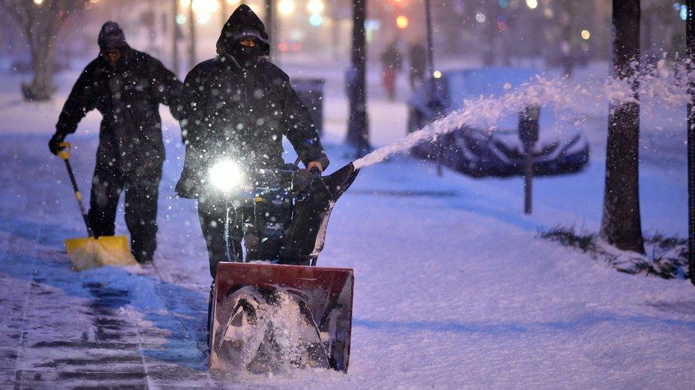 Workers clean the snow from a street in Washington DC.