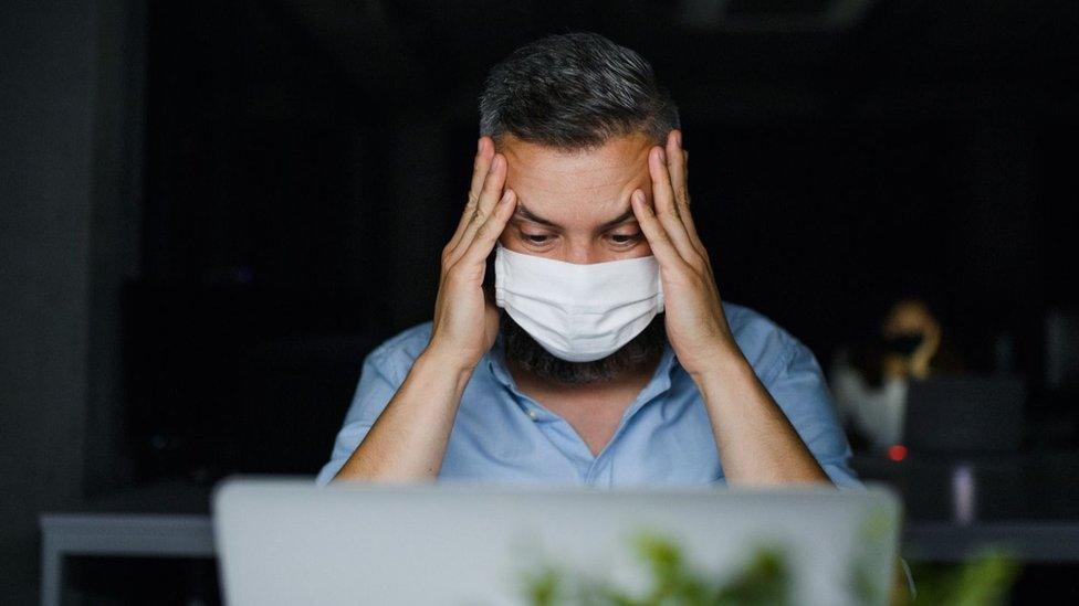 Worried man in mask looks at computer