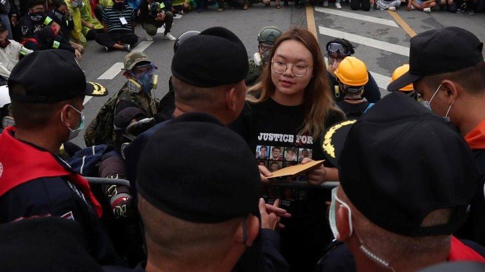 A student protest leader hands over a letter to Royal Guard police, with demands for reforming the monarchy