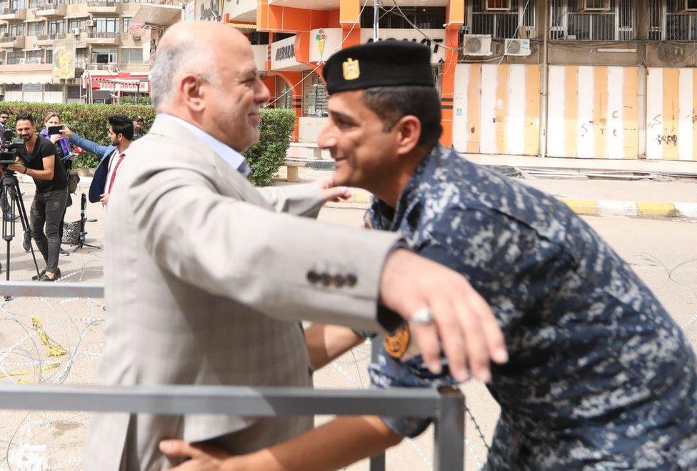 Prime Minister Haider al-Abadi is searched before entering a polling station in Baghdad, 12 May 2018