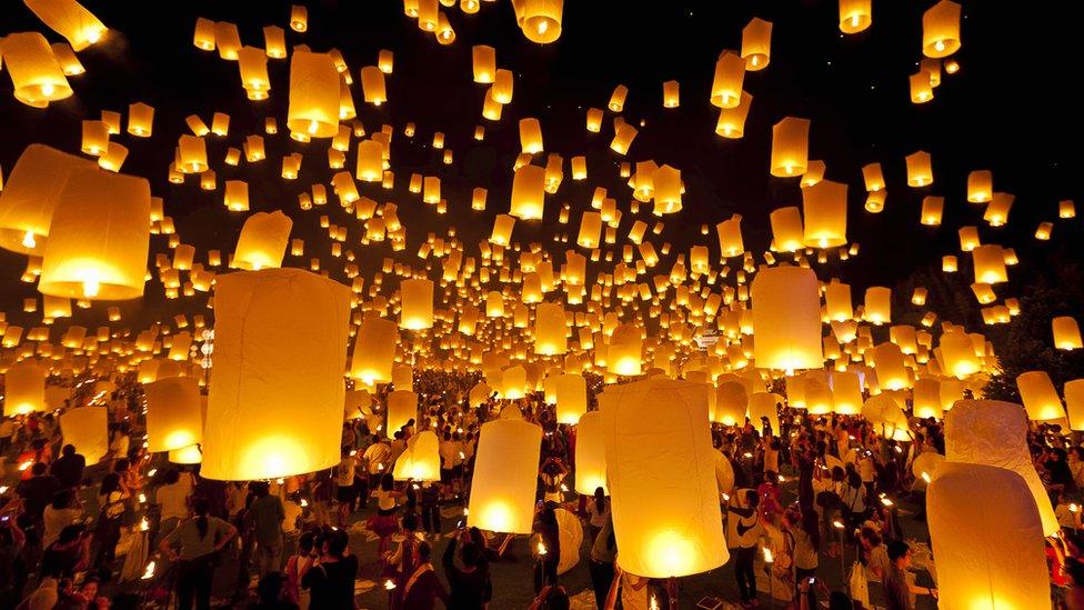 Lots of fire lit lanterns being released into the sky at night