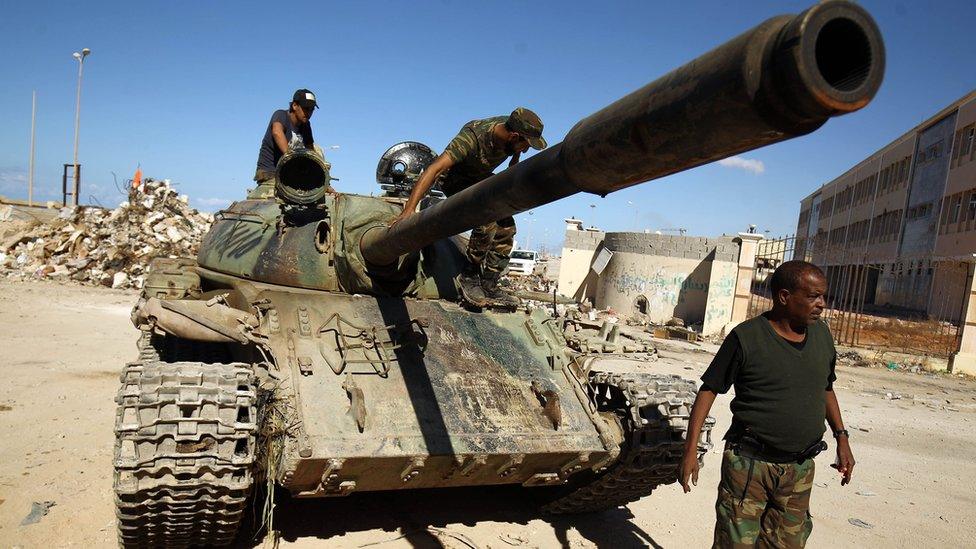 A picture taken on 9 November 2017 shows members of the self-styled Libyan National Army, loyal to the country's east strongman Khalifa Haftar, riding on a tank as it drives down a street in Benghazi