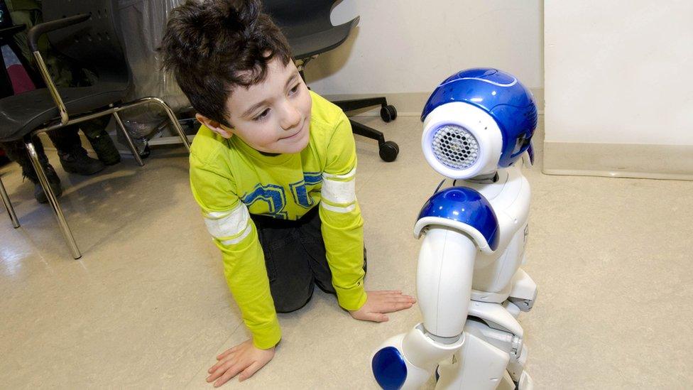 Boy kneeling and interacting with robot