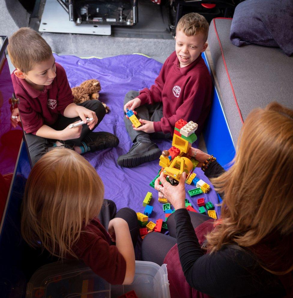 All three children and mentor build a construction out of Lego