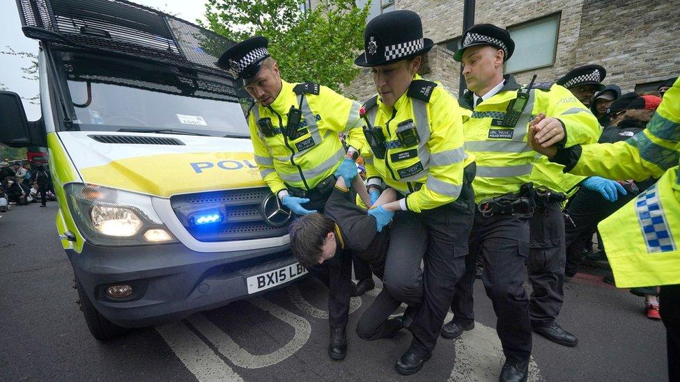 Police remove a protester after demonstrators formed a blockade around a coach