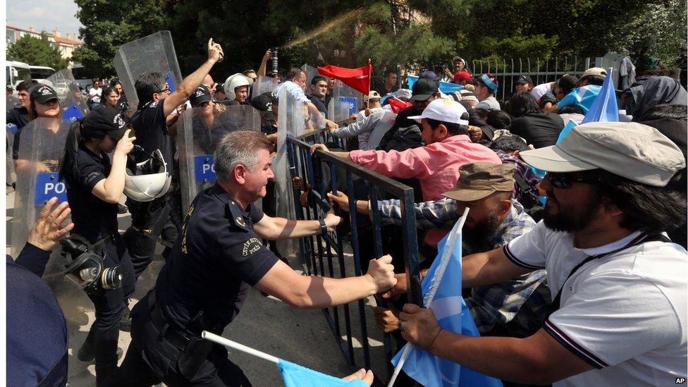 Riot police use pepper spray to push back a group of Uighur protesters who try to break through a barricade outside the Chinese Embassy in Ankara, Turkey, Thursday, June 9. 2015.