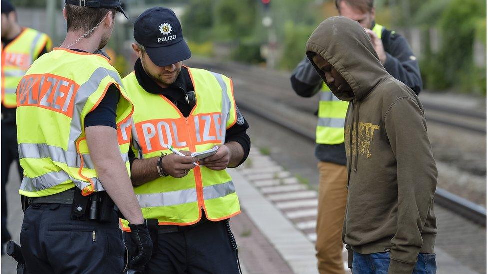 German policemen check a 16 year-old boy from Eritrea after finding him under a train trailer at the train station in the southern German city of Raubling on August 24, 2017