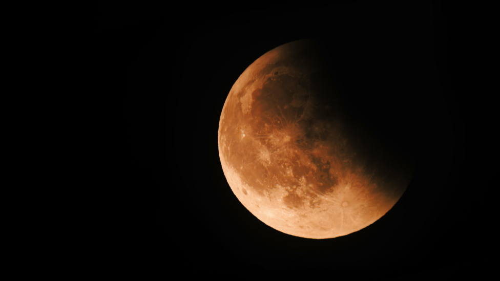An orange moon in the dark night sky.