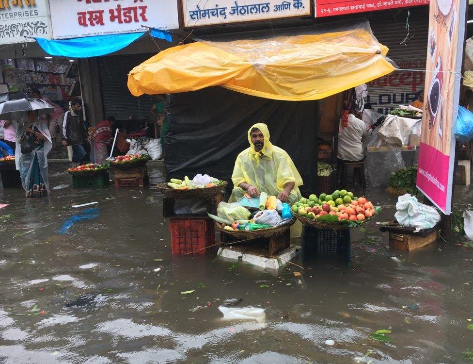 A vegetable seller sits at his stall, amid a flood left by the heavy rains in Mumbai.