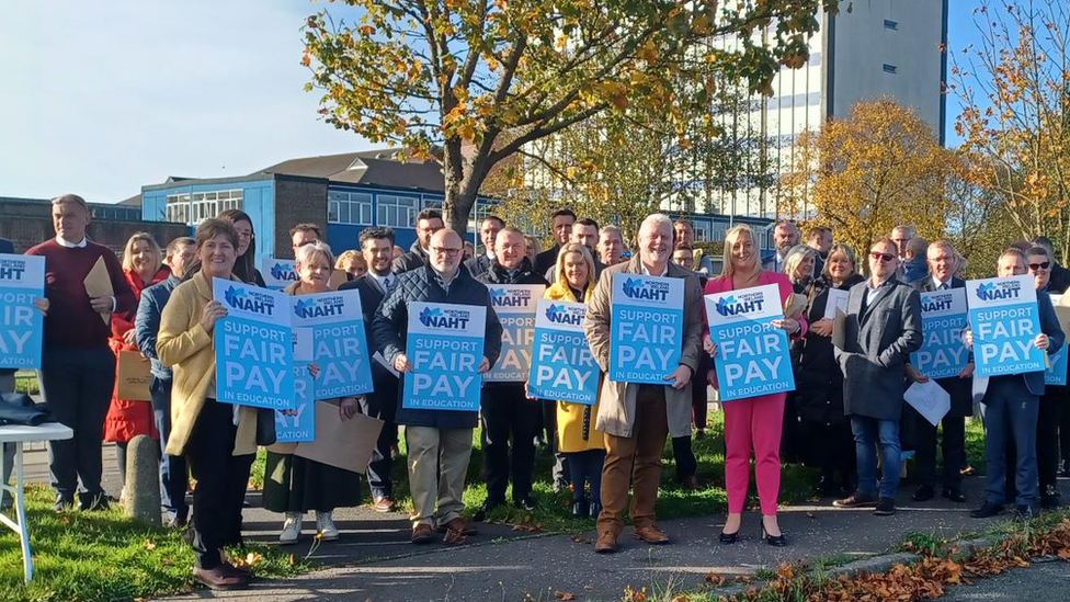 a line of people holding signs for NAHT, a headteachers' union