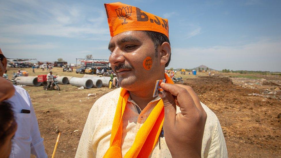 A man gets his face painted with the symbol of the Bharatiya Janata Party (BJP) before a political event addressed by India's Prime Minister Narendra Modi at the GMIT College Grounds on March 25, 2023 in Davangere