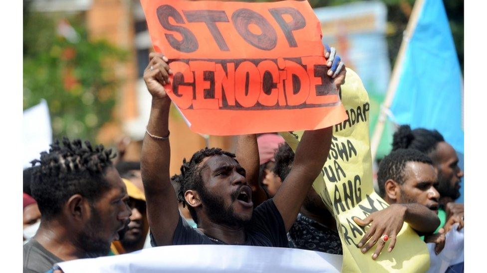 Protesters holding a banner that says "stop genocide"