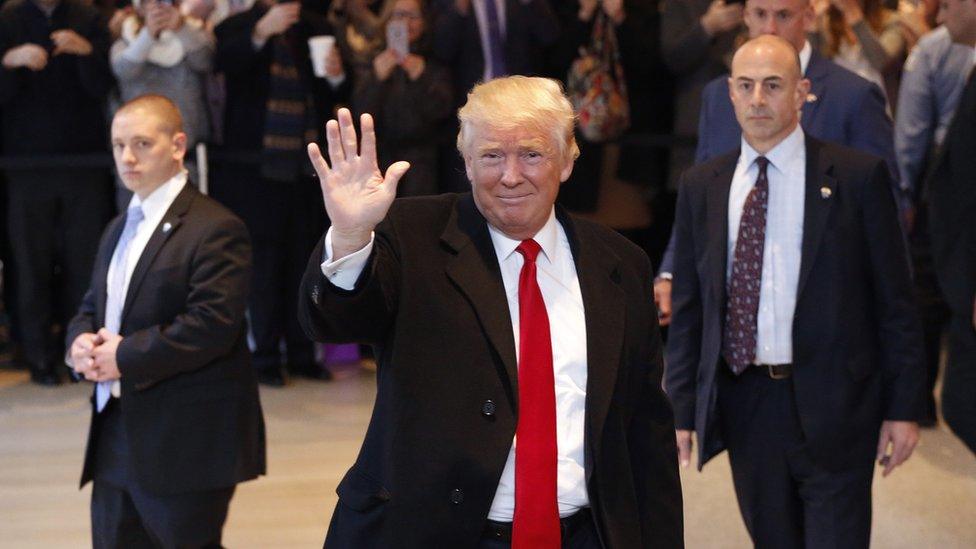 Donald Trump waves to the crowd as he leaves the New York Times building following a meeting