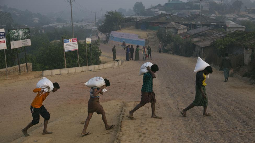 Rohingya laborers carry supplies in a refugee camp on December 11, 2019 in Cox's Bazar, Bangladesh