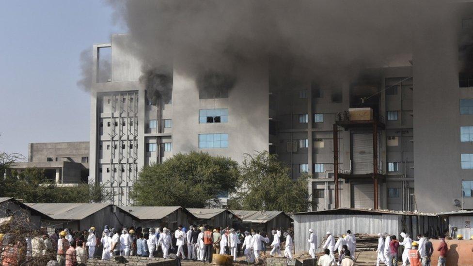 Workers stand outside the site of a deadly fire at the Serum Institute of India's facility in Pune