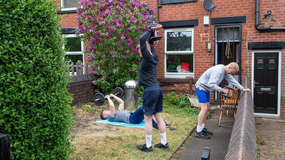 Men use gym equipment in a garden