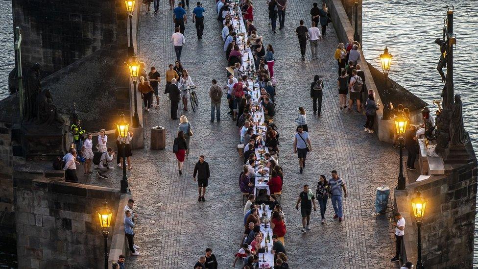 People sit at a long table on the Charles Bridge