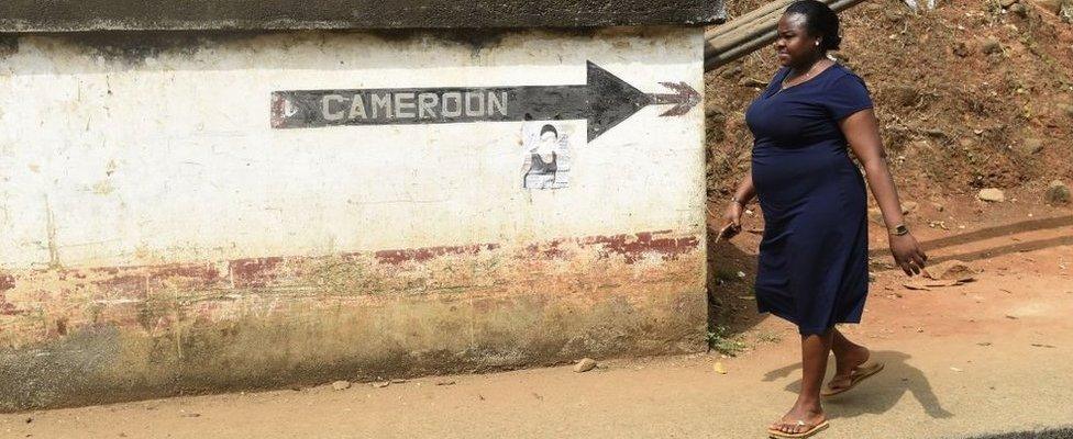 A woman walks into Nigeria from Cameroon at a checkpoint border between Cameroon and Nigeria, in Mfum, in Cross Rivers State